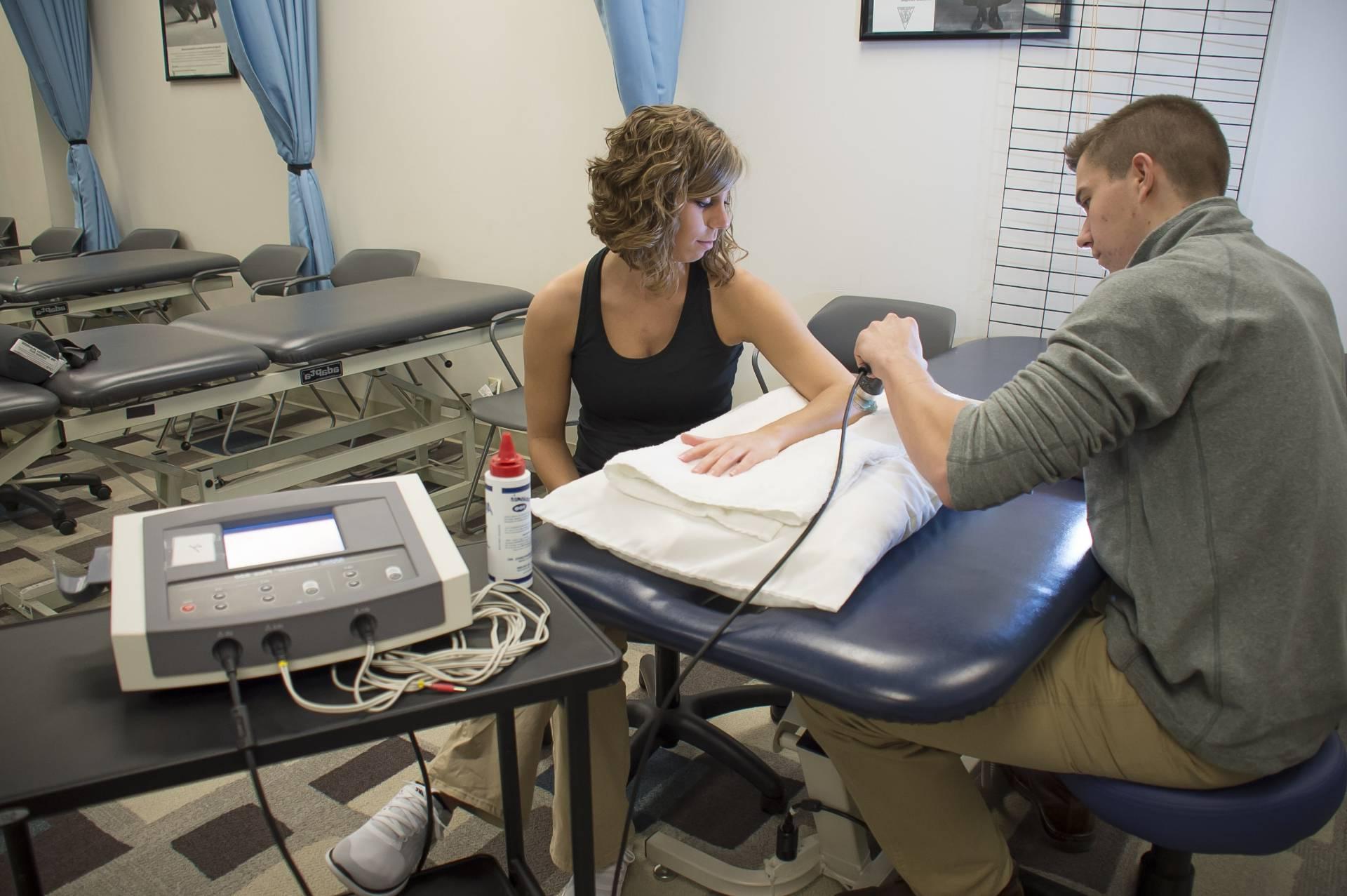 A physical therapy student examining the arm of another student