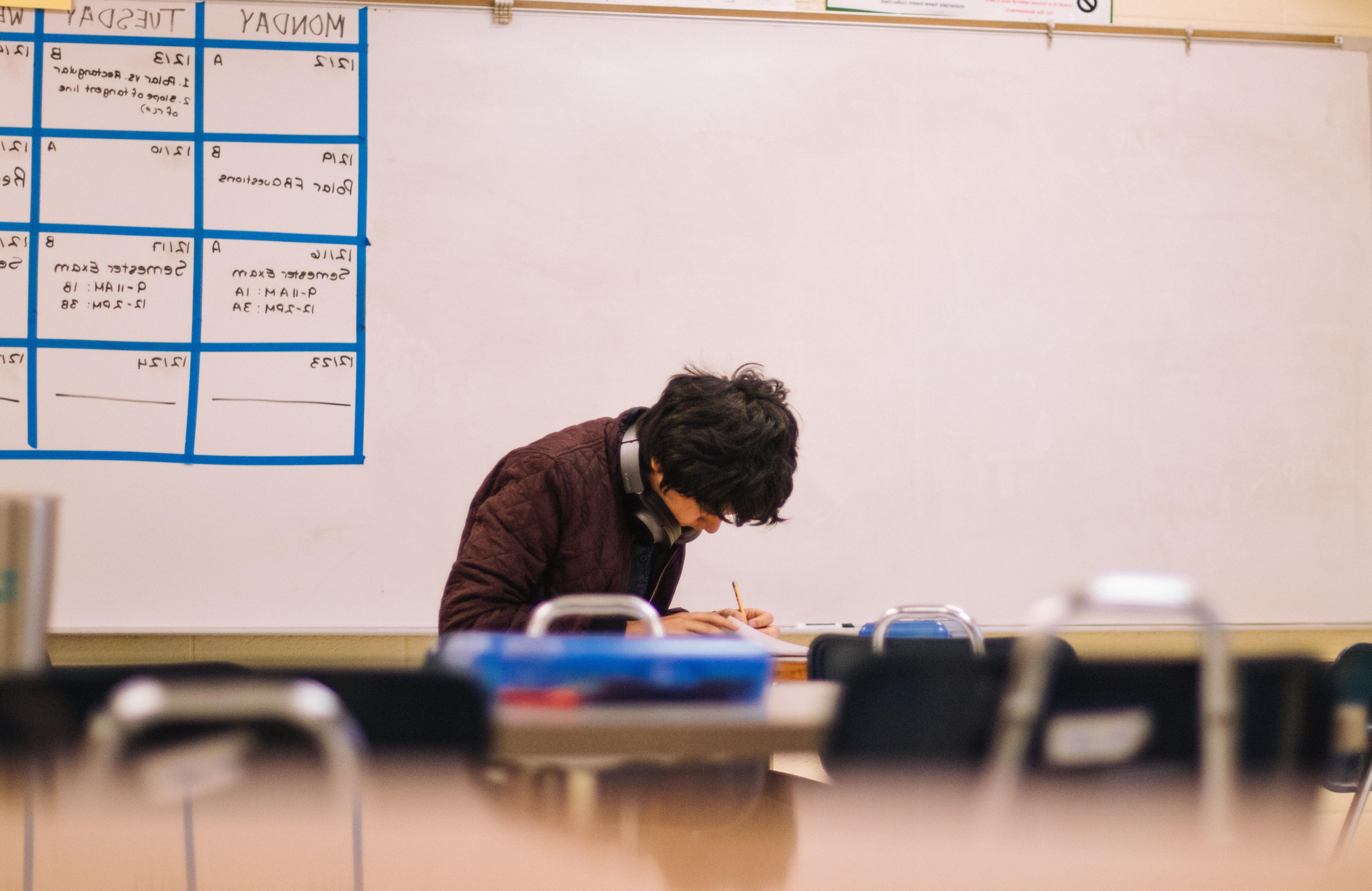 Male student hunched over at his desk